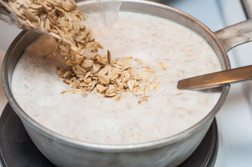 Falling oatmeal into hot milk. Steaming oatmeal.