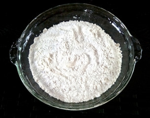 bowl of flour isolated on black background, top view