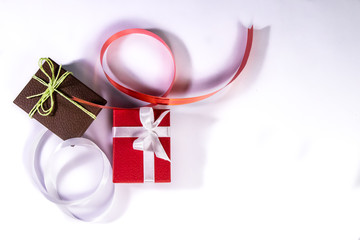 Decorated red and brown gift boxes with white and red ribbon around on white background and copy space in right