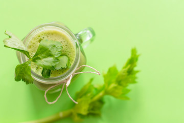 fresh celery juice in a jar on green background. concept of healthy food and detox