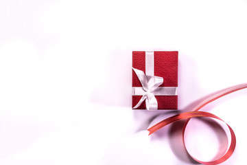 Red gift box with white ribbon isolated on white background with copy space in left side of frame