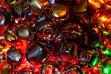 A Macro close-up image of various sized gold and chrome Jingle Bells in a glass jar with a...