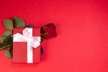 Top view of Red gift box decorated with white ribbon and red rose on red background with copy space in valentine's day concept
