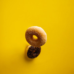 Various decorated doughnuts in motion falling on yelloy background