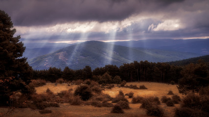 Autumnal scene with sun rays, clouds and mountains