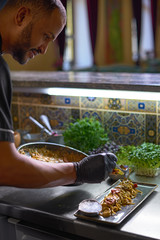 The chef mixes spaghetti in a pan the tomatoes and oysters, dish in a restaurant.