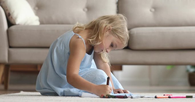 Cute kid girl playing drawing with felt pen on floor