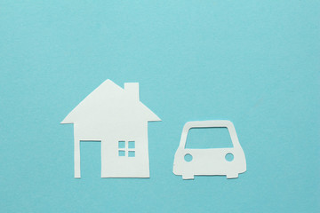 White paper cut of home and car with copy space on blue background. Goals of life.