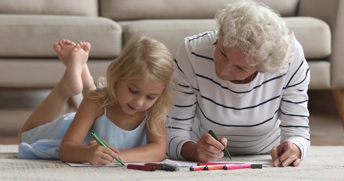 Old grandma teach little granddaughter drawing with felt pen together