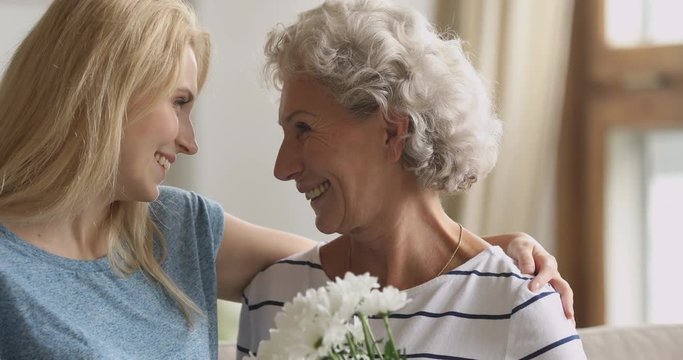 Young daughter hugging happy senior mom congratulating with mothers day