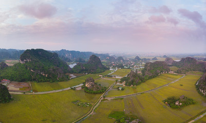 Aerial view unique sunset sky at Ninh Binh region, Trang An Tam Coc tourist attraction, UNESCO World Heritage Site, scenic river crawling through karst mountain ranges in Vietnam, travel destination.