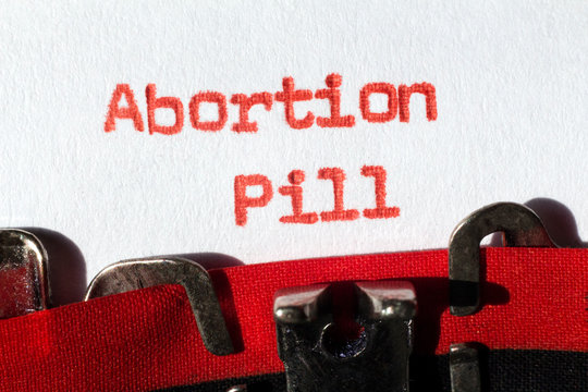Abortion pill typed on typewriter on red