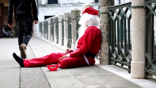 The poor man dressed as Santa begs for alm