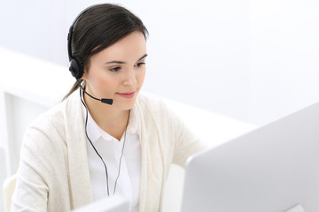 Call center. Beautiful woman receptionist sitting in headset at customer service office. Group of operators at work. Business concept