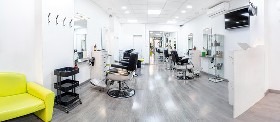Panorama of a modern bright hair and beauty salon. Barber salon interior business with black and white luxury decor. - obrazy, fototapety, plakaty
