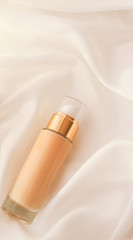 Tonal bb cream bottle make-up fluid foundation base for nude skin color on silk background,...