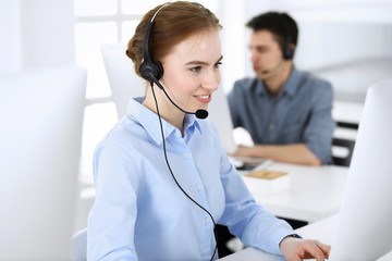 Group of operators at work. Call center. Focus on beautiful woman receptionist in headset at customer service. Business concept and casual clothing style