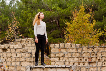beautiful girl stands on stone wall