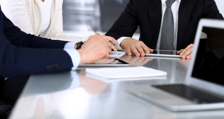 Business people discussing contract working together at meeting at the glass desk in modern office. Unknown businessman and woman with colleagues or lawyers at negotiation. Teamwork and partnership