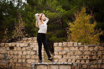 beautiful girl stands on stone wall