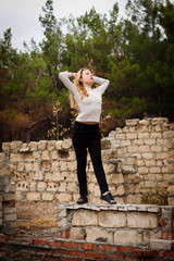 beautiful girl stands on stone wall