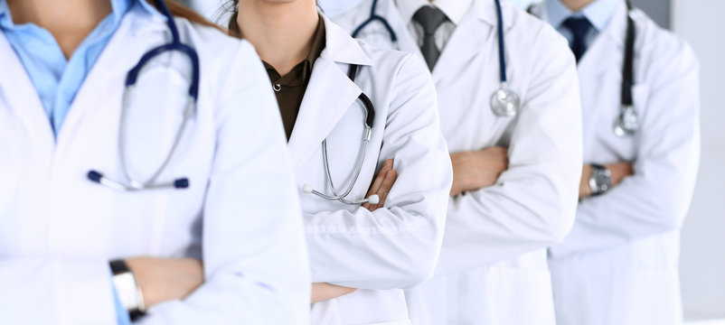 Group of modern doctors standing as a team with arms crossed in hospital office. Physicians ready to examine and help patients. Medical help, insurance in health care, best desease treatment and