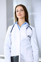 Doctor woman happy and cheerful while standing in hospital office at highlight background. Medicine and healthcare concept