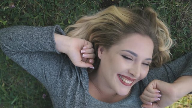 Joyful Young Woman Laugh Lie on Grass Closeup. Pretty Caucasian Girl Smile Close Eyes Nature Lawn Background. Blonde Female Adult Cover Face by Hands Fool Around Game Happy Moments Slow Motion 4K