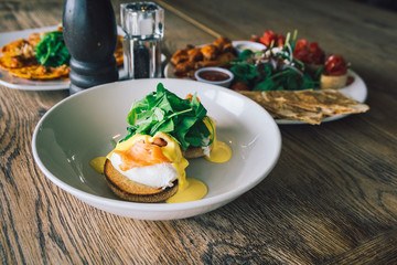 Eggs Benedict with smoked salmon and hollandaise sauce on a wooden table.