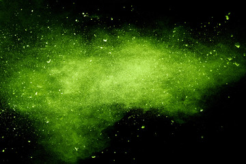 Green powder explosion on black background.Green dust particles splash.