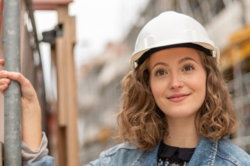 Close up portrait of a pretty and young female engineer wearing a white protective helmet