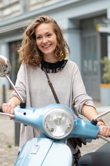 Smiling and cute blonde girl posing on a motor scooter © cineberg