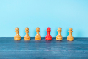 Standing out of the crowd and leadership concept, red pawn between typical chess figures.