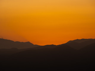 silhouettes of mountains at sunset with high orange contrast