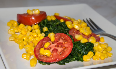 tomato, corn and spinach salad close-up view, diet and health concept