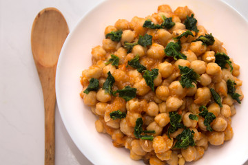 bowl of cooked chickpeas with spinach closeup view