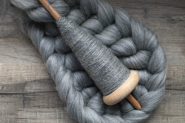 Selbst gesponnenes Garn auf der Handspindel mit grauer Wolle