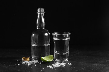 Vodka in shot glass and mini bottle on black background with a blank space for a text, Russian...