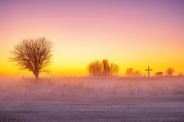 Sunset and cold mist in a wintry landscape