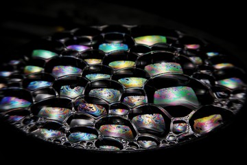 Close up of the Colorful bubbles on a black background. Refection of the Soap bubbles on the water surface on black background. 