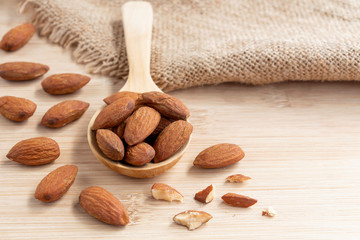 Almonds nut peeled on the wooden spoon with sackcloth on wood table background.
