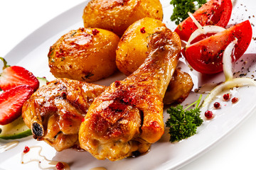 Grilled chicken drumsticks with baked potatoes and vegetables