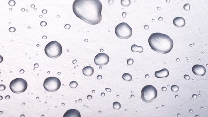 dots of water on light metal surface, macro background, horizontal shot