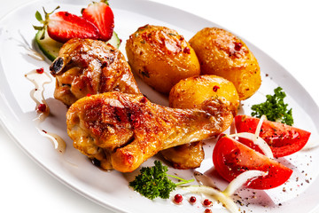 Grilled chicken drumsticks with baked potatoes and vegetables