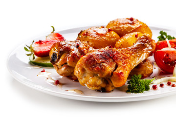 Grilled chicken drumsticks with baked potatoes and vegetables