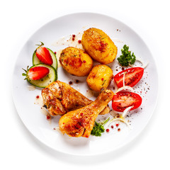 Grilled chicken drumsticks with baked potatoes and vegetables