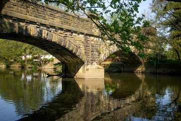 Fototapeta na wymiar A stone bridge arches over the tranquil waters of the River Aire at Cottingley in Yorkshire