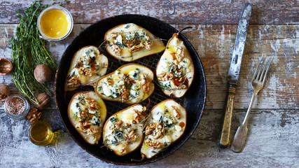 Selective focus. Baked pears with dorblu cheese and herbs.