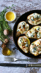 Selective focus. Baked pears with dorblu cheese and herbs.