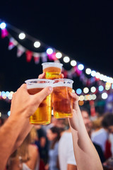 Friends drinking beer at night with de-focused lights in the background. Shallow focus.